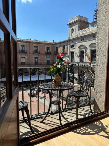 a balcony with a table and chairs and a vase of flowers at El Balcón del Mercado Chico in Ávila