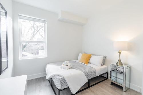 a white bedroom with a bed and a window at Beautifully Furnished 3BR Apartment Close to High Park Neatest Intersection Lane N Bloor E Indian Rd in Toronto