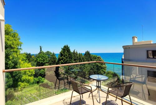 a balcony with chairs and a table and the ocean at Cabacum Pleasure Beachfront Apartments in Varna City