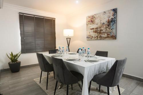 a dining room with a white table and chairs at Self made Estates in Accra