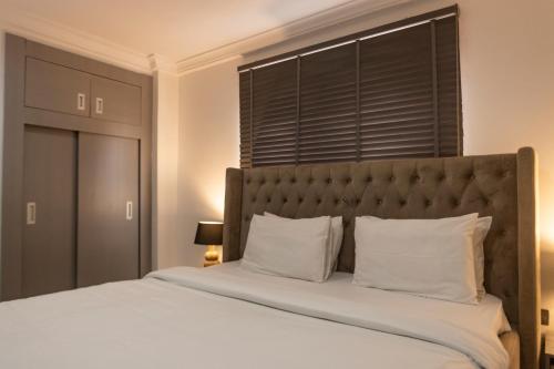 a bedroom with a large bed with white sheets and pillows at Self made Estates in Accra