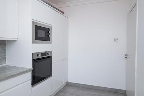 a white kitchen with a stove and a microwave at Self made Estates in Accra