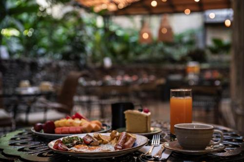 a table with plates of food and a glass of orange juice at Hotel Poblado Alejandria in Medellín