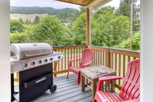 a grill on a deck with two chairs and a table at Nehalem Coastal Oasis - Secluded Coastal Home with Hot Tub on 14 Acres in Nehalem