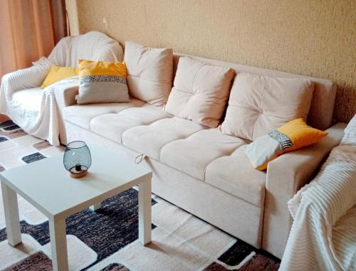 a living room with a white couch and a table at 2х комнатная квартира в центре in Ustʼ-Kamenogorsk