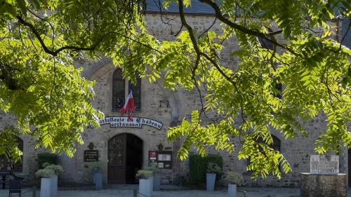 a stone building with a flag in front of it at L'Hostellerie du Château de Bricquebec in Bricquebec