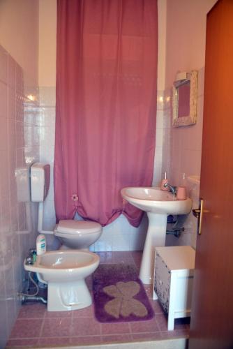 a bathroom with a pink shower curtain and a toilet and sink at Villino Anna e Pippino in Calatafimi