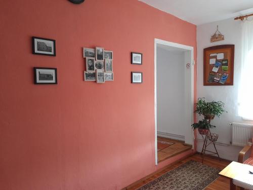 a room with an orange wall with pictures on it at Lipowy Dwór in Laskówka