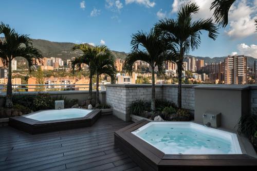 two hot tubs on a deck with palm trees at Hotel Poblado Alejandria in Medellín