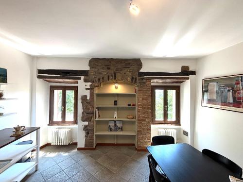 a living room with a table and a brick wall at Residenza La Rocca 1227 - Borgo Castello di Serravalle in Castello di Serravalle