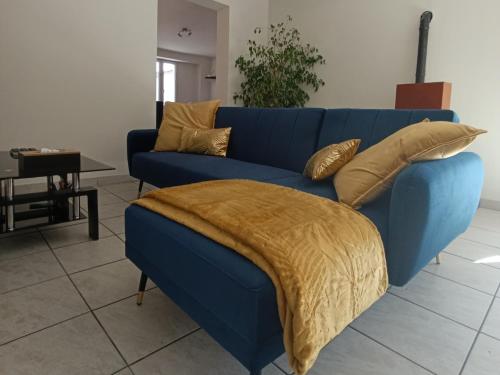 a blue couch with a blanket on it in a living room at La Maison du Sapin 