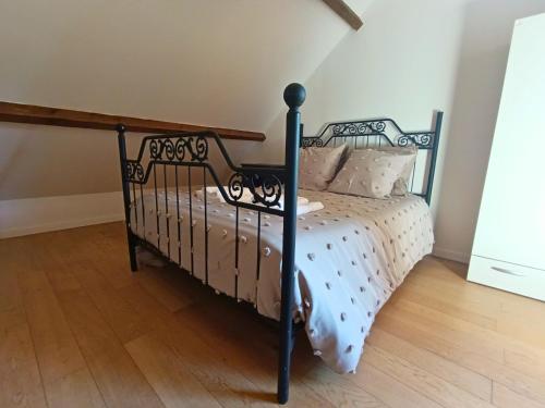a black bed in a room with a wooden floor at La Maison du Sapin 
