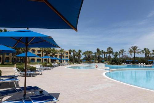 a pool at the resort with chairs and umbrellas at Verdi Tunis Beach Resort in Gammarth