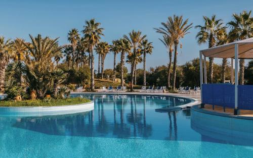 a swimming pool with palm trees and a gazebo at Verdi Tunis Beach Resort in Gammarth