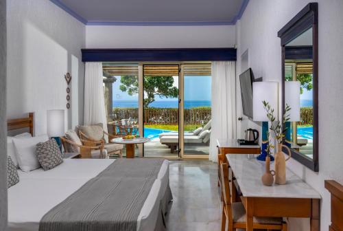 a bedroom with a bed and a view of the ocean at Leptos Panorama Hotel in Kalamaki Chanion