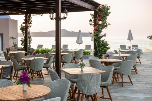 a patio with tables and chairs with a view of the ocean at Leptos Panorama Hotel in Kalamaki Chanion