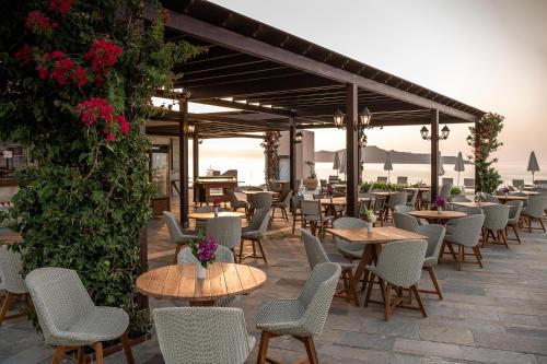 a patio with tables and chairs and flowers at Leptos Panorama Hotel in Kalamaki Chanion