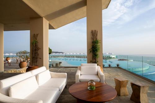 a living room with white furniture and a view of a pool at Leptos Panorama Hotel in Kalamaki Chanion