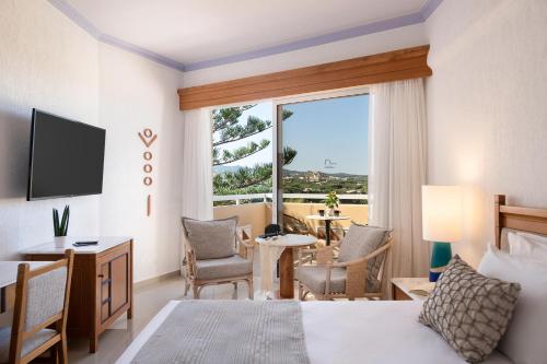 a hotel room with a bed and a large window at Leptos Panorama Hotel in Kalamaki Chanion