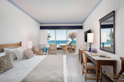 a bedroom with a bed and a living room with the ocean at Leptos Panorama Hotel in Kalamaki Chanion
