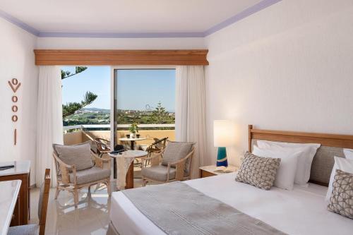 a bedroom with a bed and a table and chairs at Leptos Panorama Hotel in Kalamaki Chanion