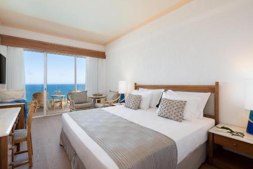 a hotel room with a bed with a view of the ocean at Leptos Panorama Hotel in Kalamaki Chanion