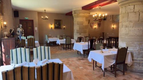 a restaurant with white tables and chairs and a statue at L'Hostellerie du Château de Bricquebec in Bricquebec