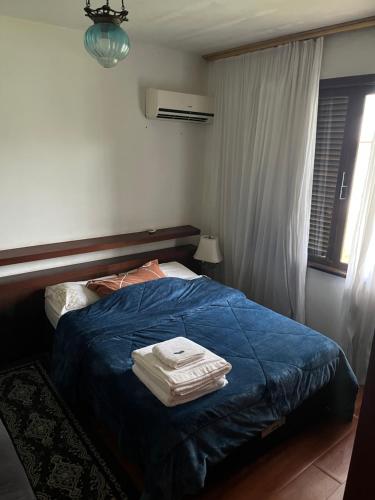 a bedroom with a bed with a blue blanket and a window at Suíte do Morro in Pomerode