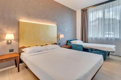 a hotel room with two beds and a window at B&B HOTEL Bergamo Executive in San Paolo D'Argon