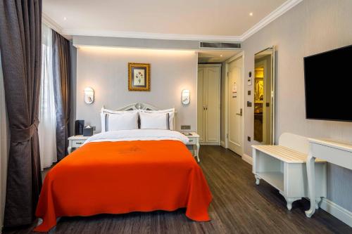 a hotel room with a bed with an orange blanket at Amiral Palace Hotel Boutique Class in Istanbul
