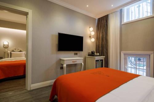 a hotel room with a bed and a flat screen tv at Amiral Palace Hotel Boutique Class in Istanbul