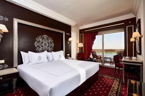 Cette chambre comprend un grand lit blanc et une grande fenêtre. dans l'établissement Sonesta St. George Hotel - Convention Center, à Louxor