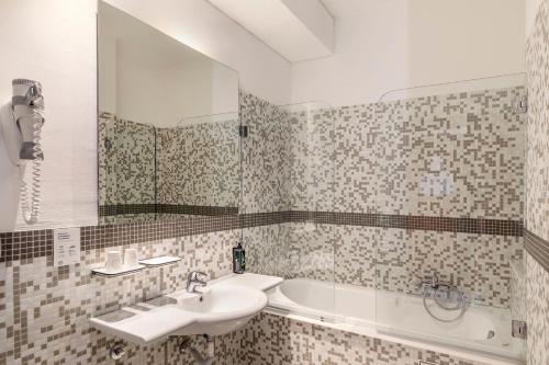 a bathroom with a sink and a tub and a mirror at B&B Hotel Modena in Modena