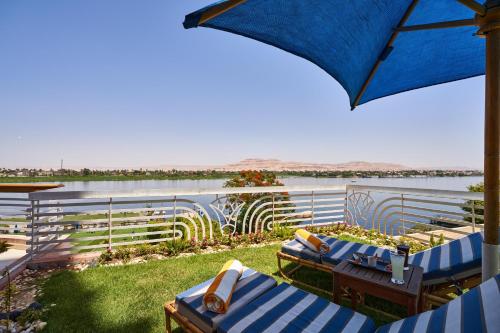 une terrasse avec des chaises bleues et blanches et un parasol dans l'établissement Sonesta St. George Hotel - Convention Center, à Louxor