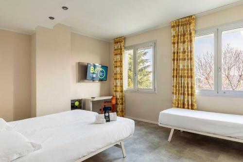 a bedroom with two beds and a tv and windows at B&B Hotel Modena in Modena