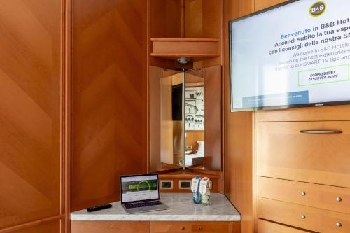 a laptop on a counter in a room with a tv at B&B Hotel Modena in Modena