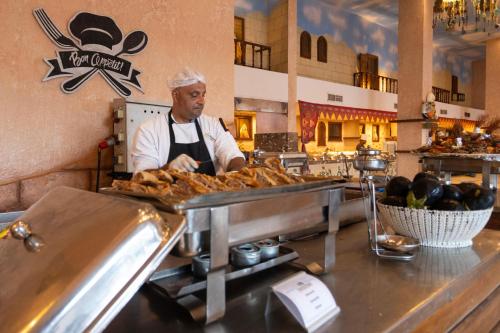 a man in a kitchen preparing food in a restaurant at Sunny Days El Palacio Resort & Spa in Hurghada