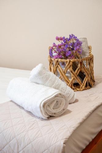 a pair of towels and a basket of flowers on a bed at Filoxenia Apartments in Mytilini