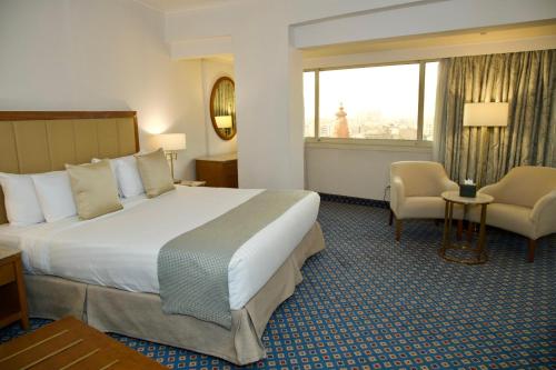 a hotel room with a large bed and a chair at Baron Hotel Cairo in Cairo