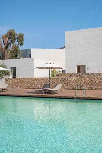 a pool of water with two chairs and an umbrella at Voyage Torba Hotel in Torba