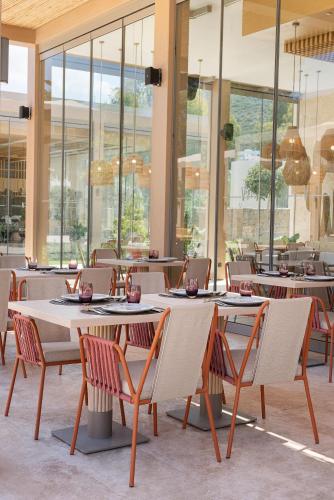 a restaurant with tables and chairs and windows at Voyage Torba Hotel in Torba
