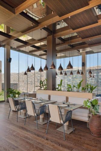 a restaurant with tables and chairs and large windows at Voyage Torba Hotel in Torba