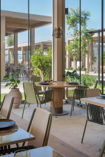 a restaurant with tables and chairs and windows at Voyage Torba Hotel in Torba
