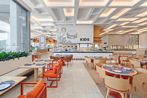 a restaurant with tables and chairs and a cafeteria at Voyage Torba Hotel in Torba