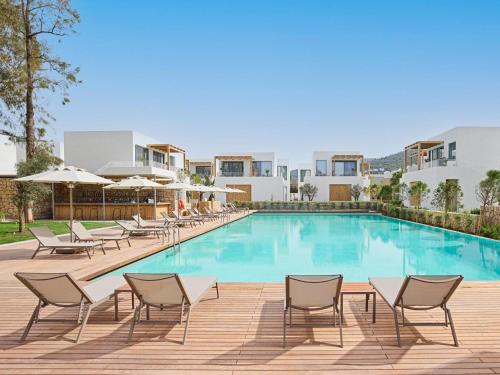 a pool at a hotel with chairs and umbrellas at Voyage Torba Hotel in Torba
