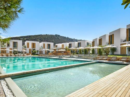a swimming pool at a resort with chairs and umbrellas at Voyage Torba Hotel in Torba