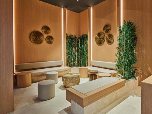 a lobby with tables and stools and plants at Voyage Torba Hotel in Torba