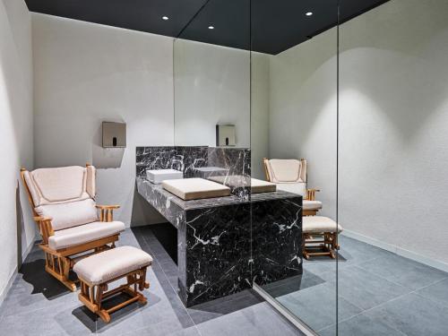 a bathroom with a black marble counter and chairs at Voyage Torba Hotel in Torba