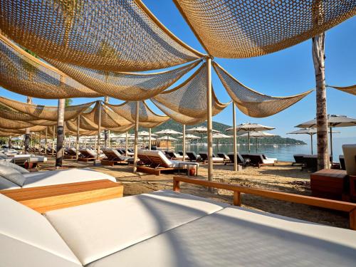 a beach with a bunch of chairs and umbrellas at Voyage Torba Hotel in Torba