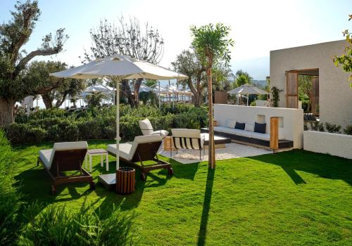 a garden with chairs and an umbrella and a couch at Voyage Torba Hotel in Torba